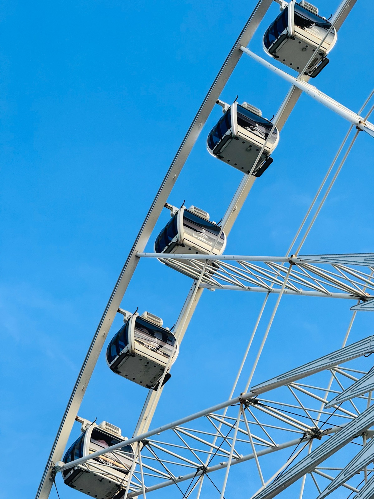 Gondolas on a white Ferris wheel against a blue sky