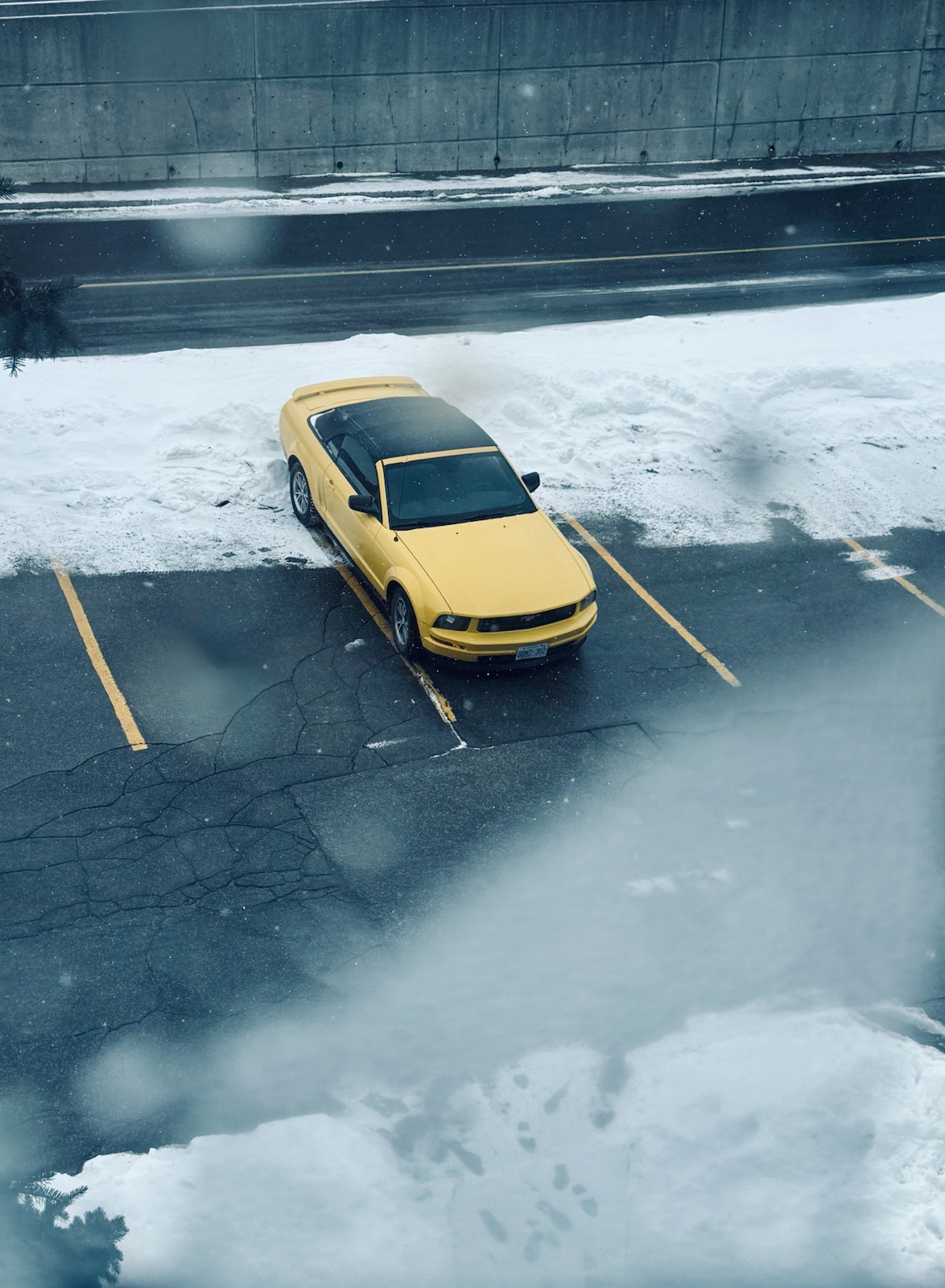 A yellow car parked in a snowy lot