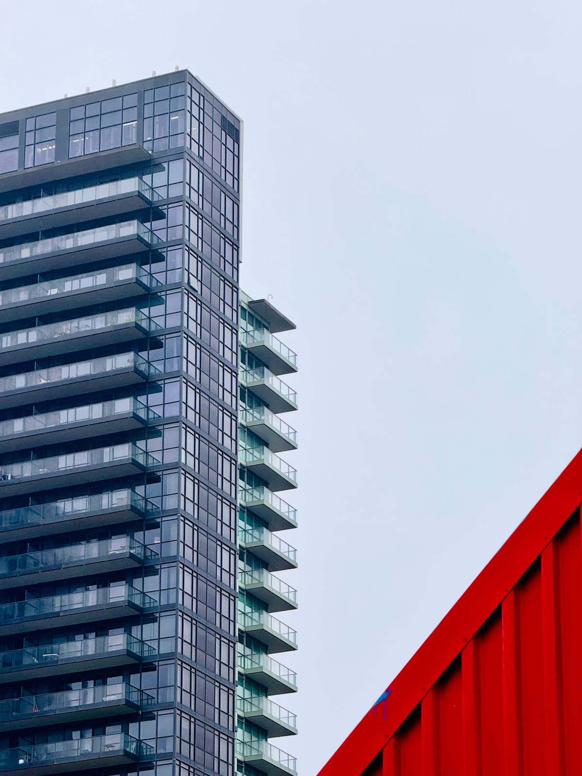 A glass tower beside a bright red wall