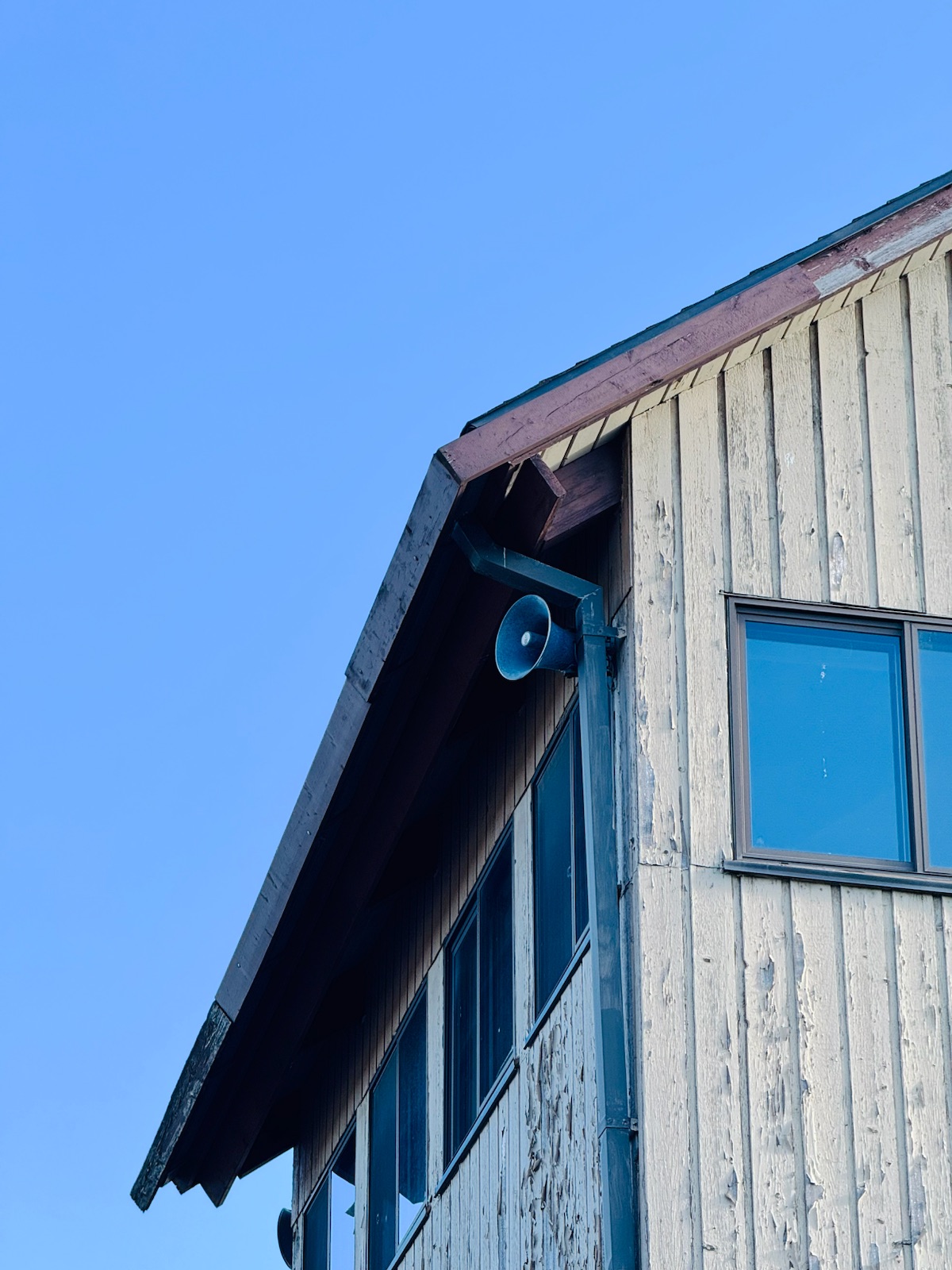 Corner of a white wooden house against a deep blue sky